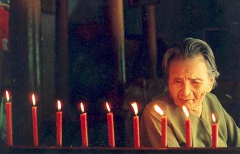 Mẹ Thứ (lúc sinh thời) với chín ngọn nến tưởng niệm chín người con của mẹ đã hy sinh trong chiến tranh. Ảnh: VŨ CÔNG ĐIỀN